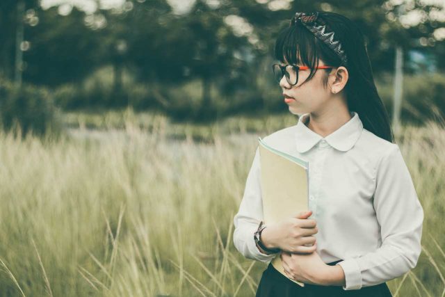 Female student wearing eyeglasses, carrying books