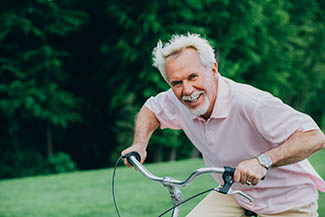 Lively Older Man Riding His Bicycle, Laughs And Enjoys Life. Sen